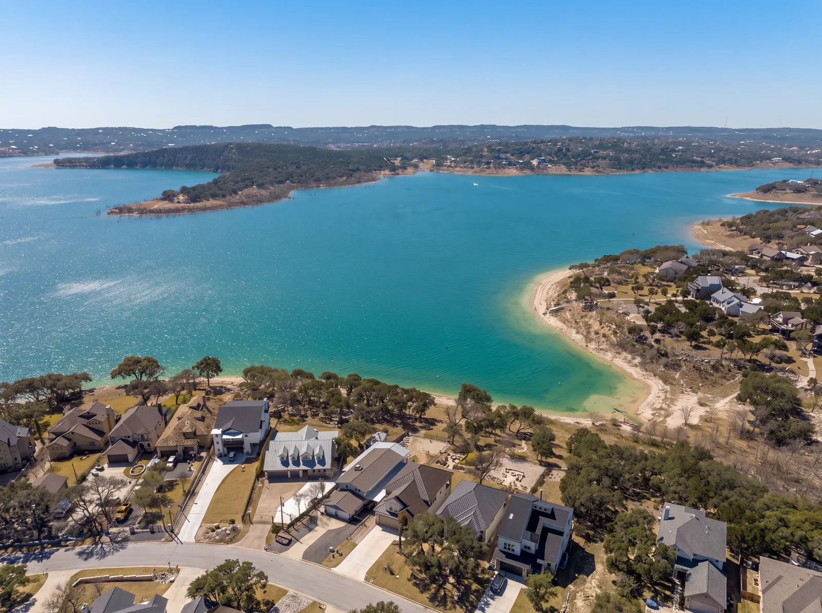 Aerial view over Canyon Lake, with the turquoise reservoir filling a river canyon and lakeside homes along the wooded shoreline