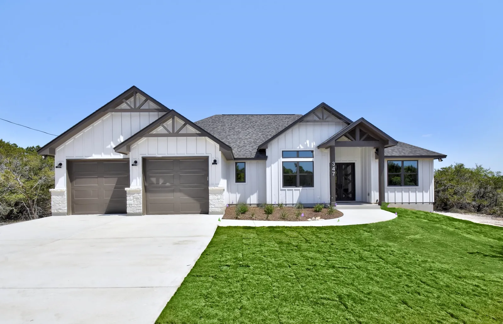 Single-story Hill Country farmhouse with a three-car garage and stone drive