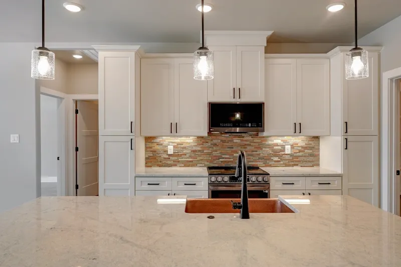 White shaker kitchen with a hammered copper apron sink set into the island