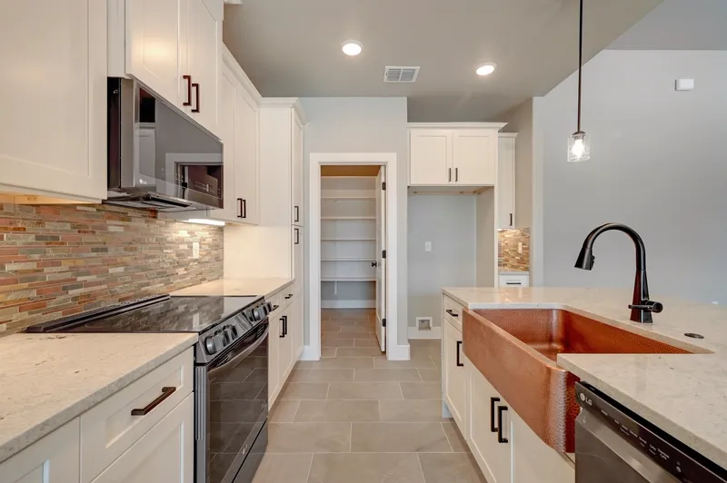 Kitchen range and tile backsplash with the walk-in pantry door alongside