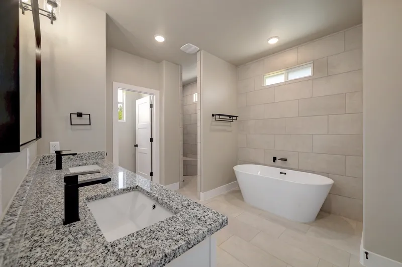 Primary bathroom with a granite vanity, freestanding tub and tiled walk-in shower