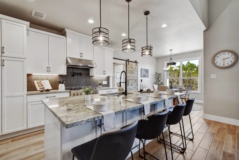 Kitchen island with pendant lighting, bar seating and white cabinetry