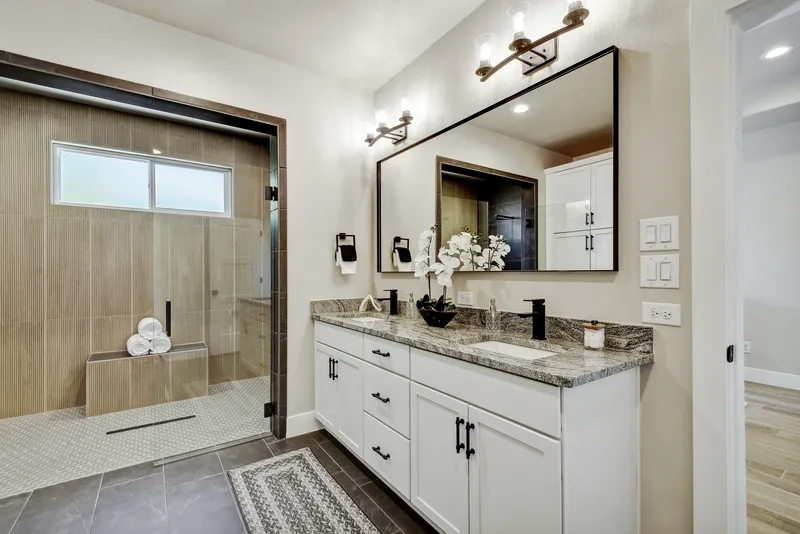 Primary bathroom with a double vanity, framed mirror and walk-in shower